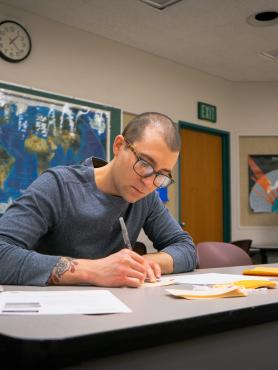 Student filling out tags with world map in background