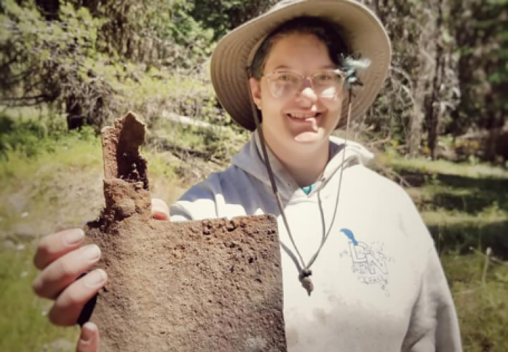 Student holding a shovel artifact recovered from gold mining complex