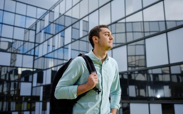 Student with backpack with building in background