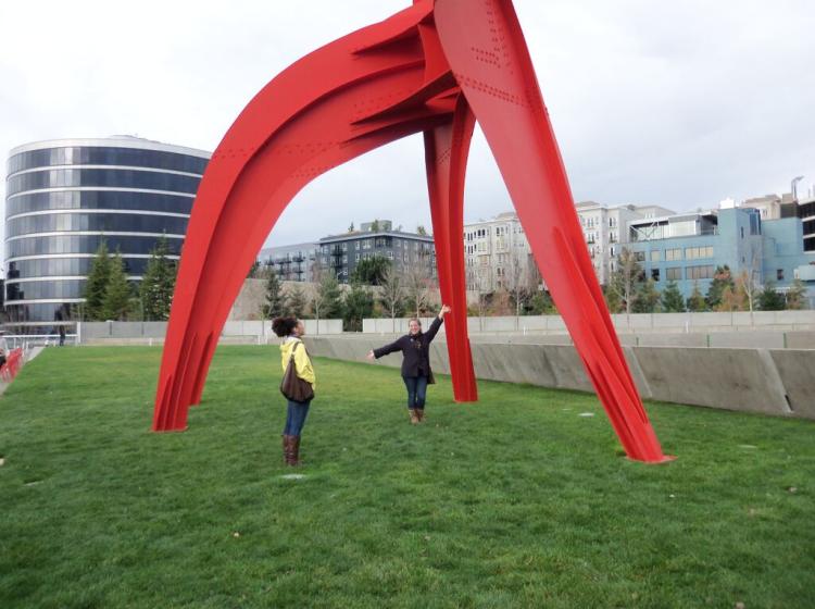Two students posing under a giant red Alexander Calder sculpture on a field trip to Seattle