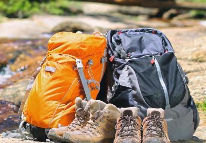Hiking boots and backpacks near a stream.