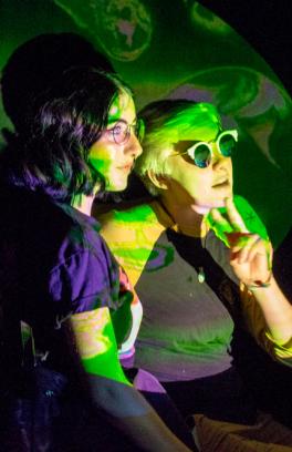 Two students illuminated by a colorful video projection