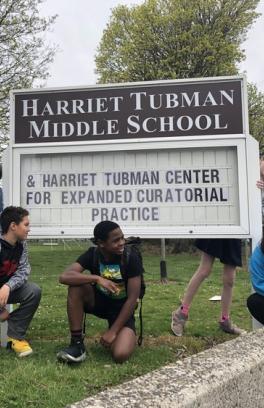 Harriet Tubman Middle School sign with students gathered around