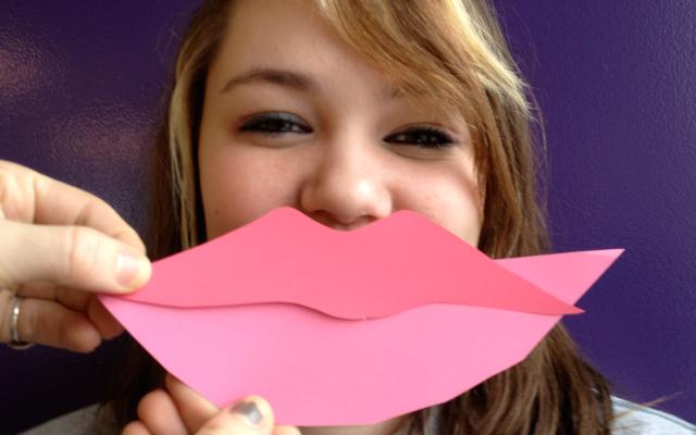 Smiling student with giant pink paper lips