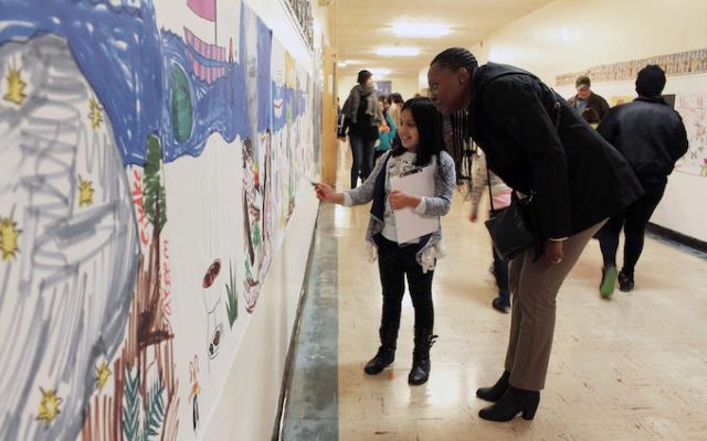 A young girl docent points to an artwork as she explains its significance to a visitor