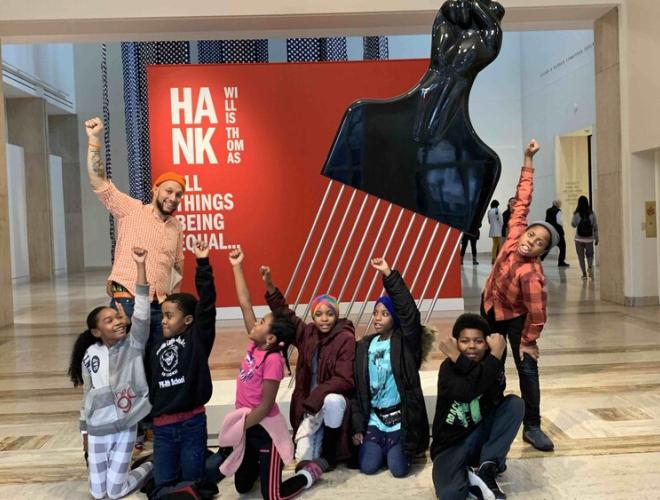 Stevenson and a group of King School students pose with fists raised in front of a sculpture by Hank Willis Thomas at the Portland Art Museum.