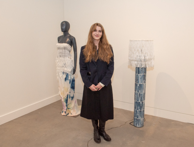 Johanna Houska standing in the gallery next to her work.