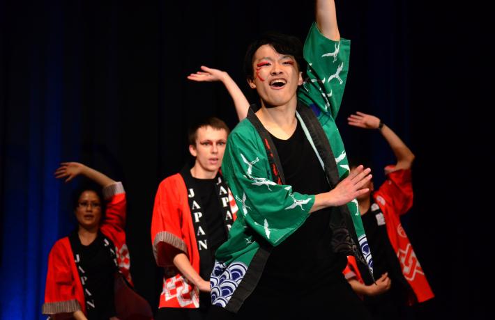 A group of students on a stage striking the same pose during a performance.