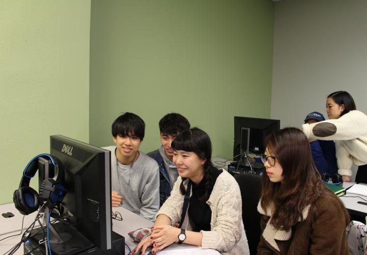 Four students clustered around a computer looking at something.