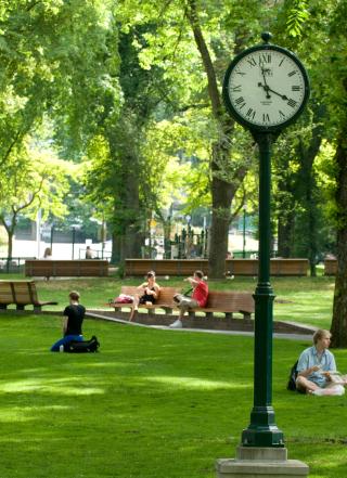 PSU Park Blocks shown with a clock. Green grass and students sitting.