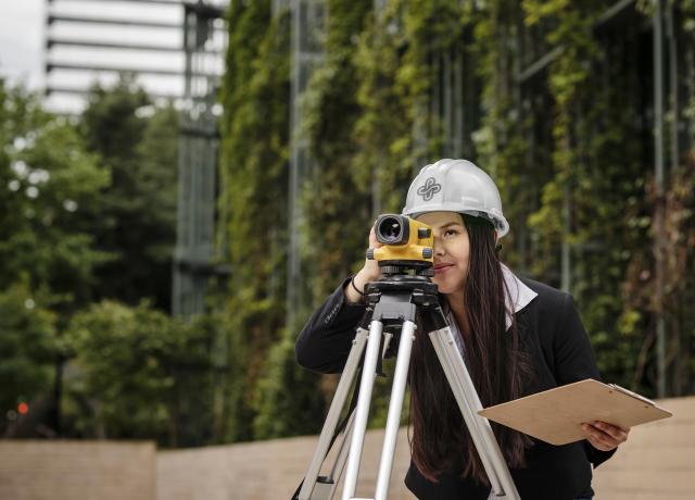 a student looks through the lens of a surveying instrument