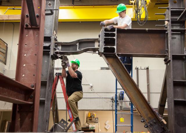 Two researchers working on a steel beam.