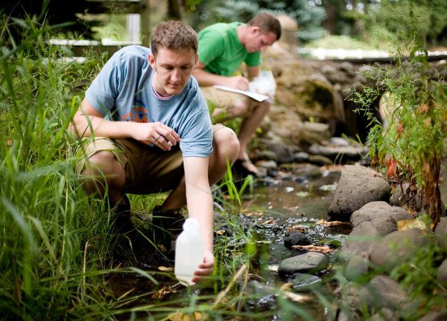 researchers collect water samples from a creek