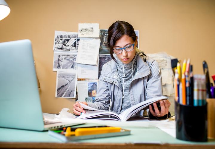Student studying at desk from a textbook
