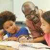 Explore our programs: A Black male teacher smiles brightly as he assists two young students with their coursework.