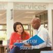 Resources for students: Two adults sit outside a Student Services building together, going over information in a blue binder.