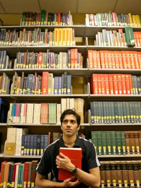 Person holding book sitting in front of stack of books