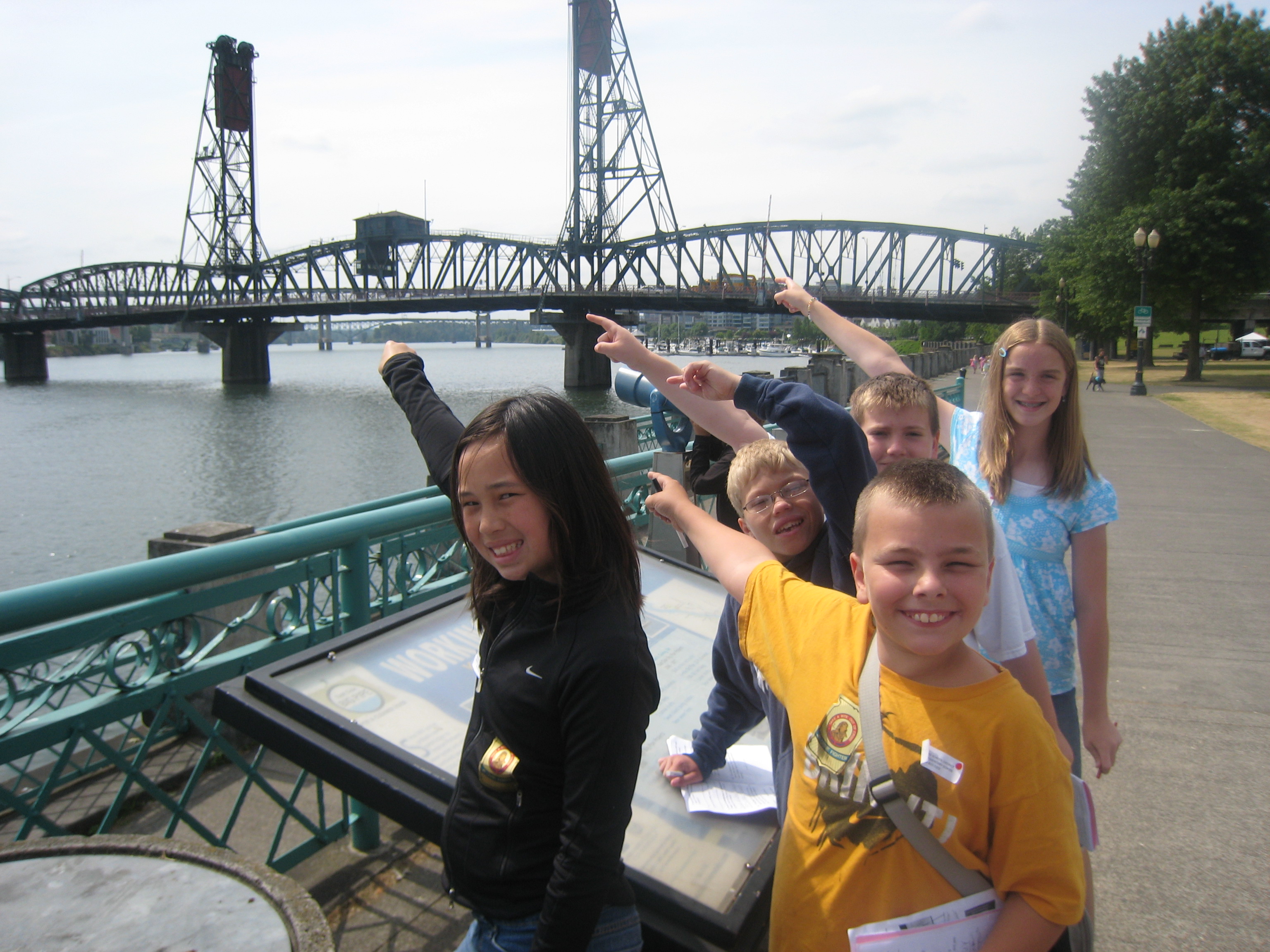 small group of children pointing at bridge over a river