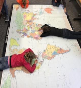 Two kids laying on their stomachs on Giant World Map