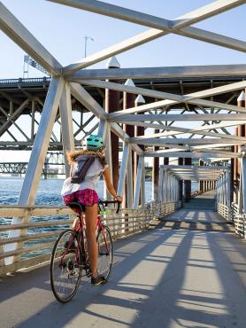 Student riding bike on bridge