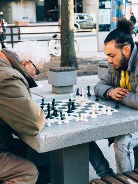 Older man and younger man playing chess in public