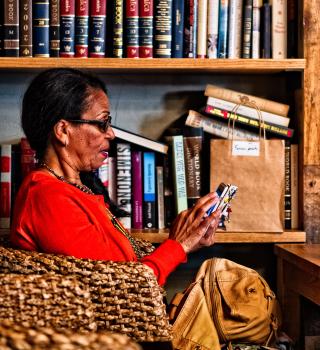 Older woman with cell phone and bookshelf