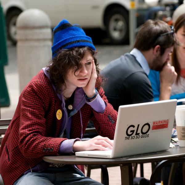 Student sitting in front of a laptop at a small table with face resting on one hand