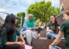 Group of four students sitting in Urban Plaza in conversation