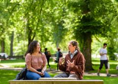 Man, woman seated on bench in conversation