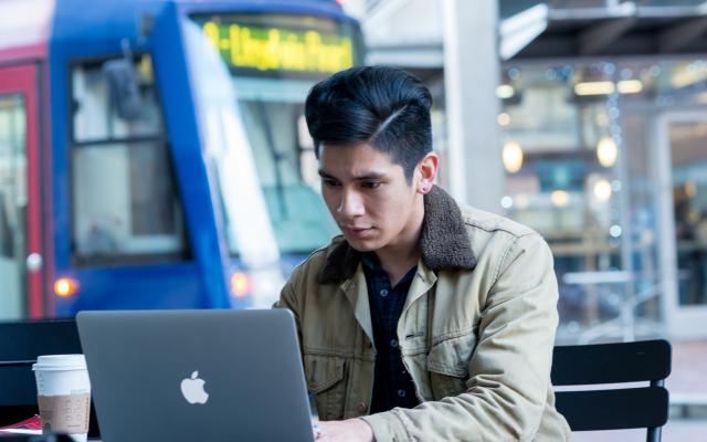 Student on laptop with streetcar in background