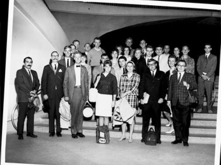 A black and white photo of students on a staircase in 1960s attire.