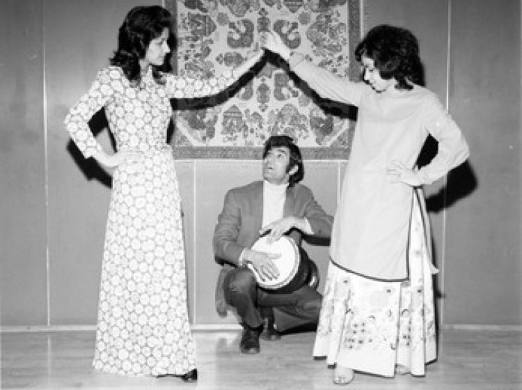 Two women dance in front of a man kneeling with a drum in rehearsal for Persian New Year event at PSU, 1972.