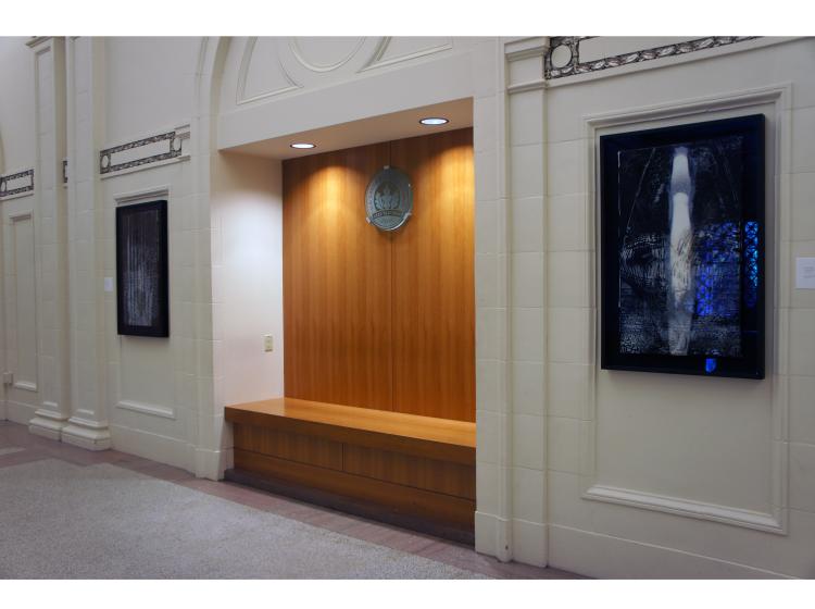 Both artworks are seen in a wide shot. Between the two is a recessed alcove with lights, a bench, and stained wood finish