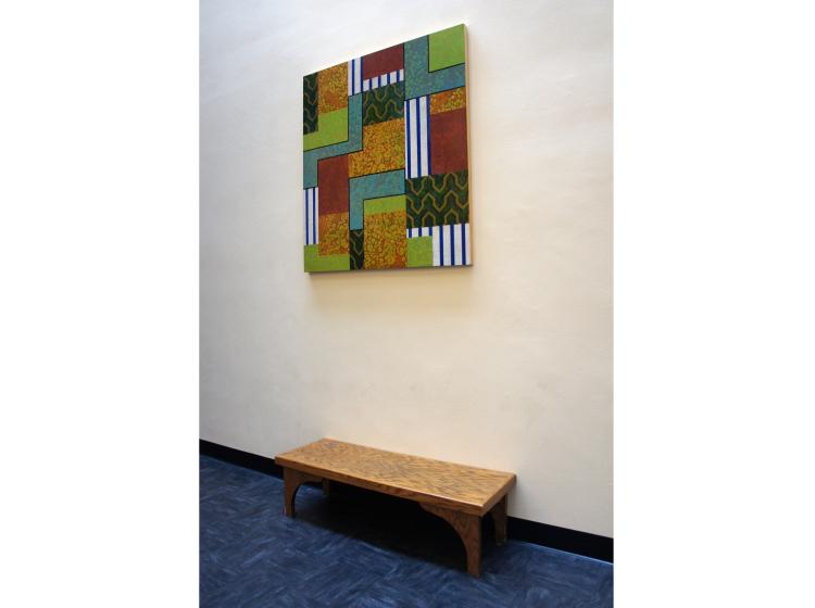 The painting is shown hung on a wall, viewed from an angle. A bench sits below the painting