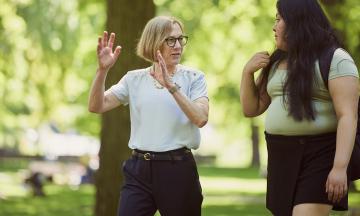 President Ann Cudd walking and talking in the Park Blocks next to a student. 