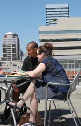 Group of three people talking at table on rooftop