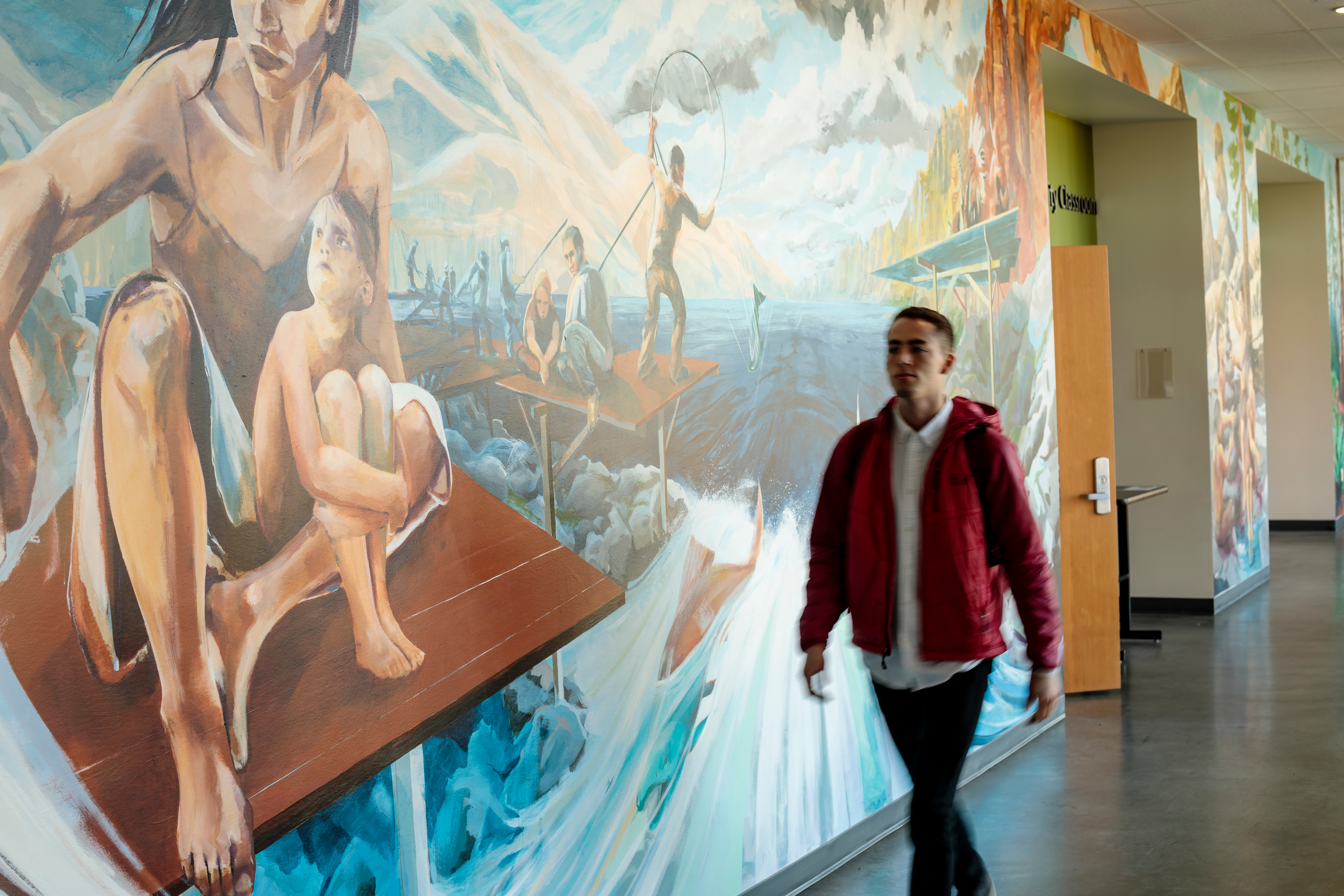 A student walks by a mural in the PSU School of Social Work