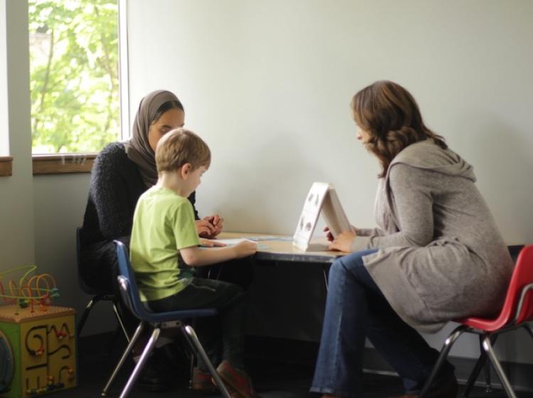 Two student research assistants conduct a vocabulary assessment with a preschooler.