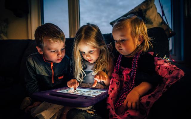 Three children looking at a tablet