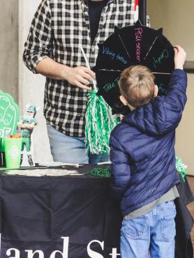 A kid at a Portland State University booth is spinning a prize wheel to see what he wins..