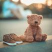 A teddy bear sitting next to a pair of shoes.
