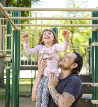 A smiling Father and Child in the Park Block Playground.