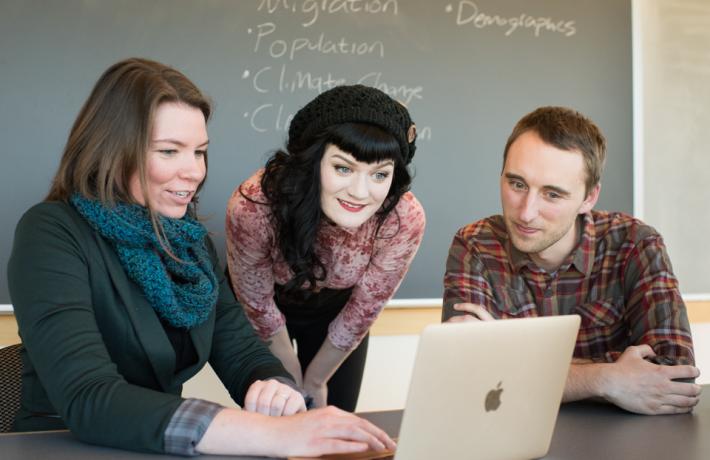 Three students sharing a laptop