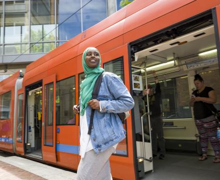 A student walking out of a Portland Streetcar in the PSU Urban Center Plaza