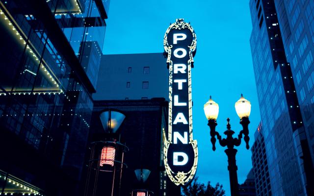 The word 'Portland' displayed vertically on a building sign at night.