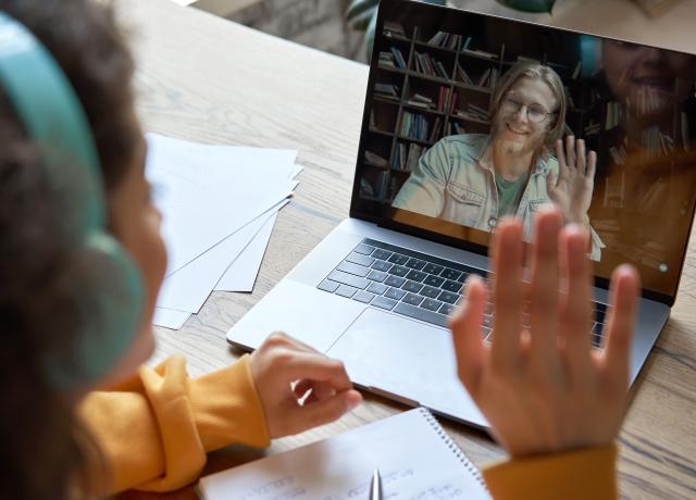 faculty waving to student with headphones on screen