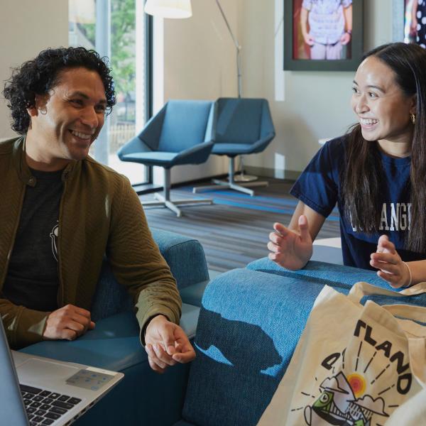 man and woman smiling while talking and looking at a computer