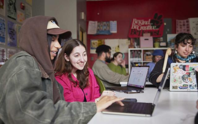Faculty and student looking a digital course materials together in a classroom