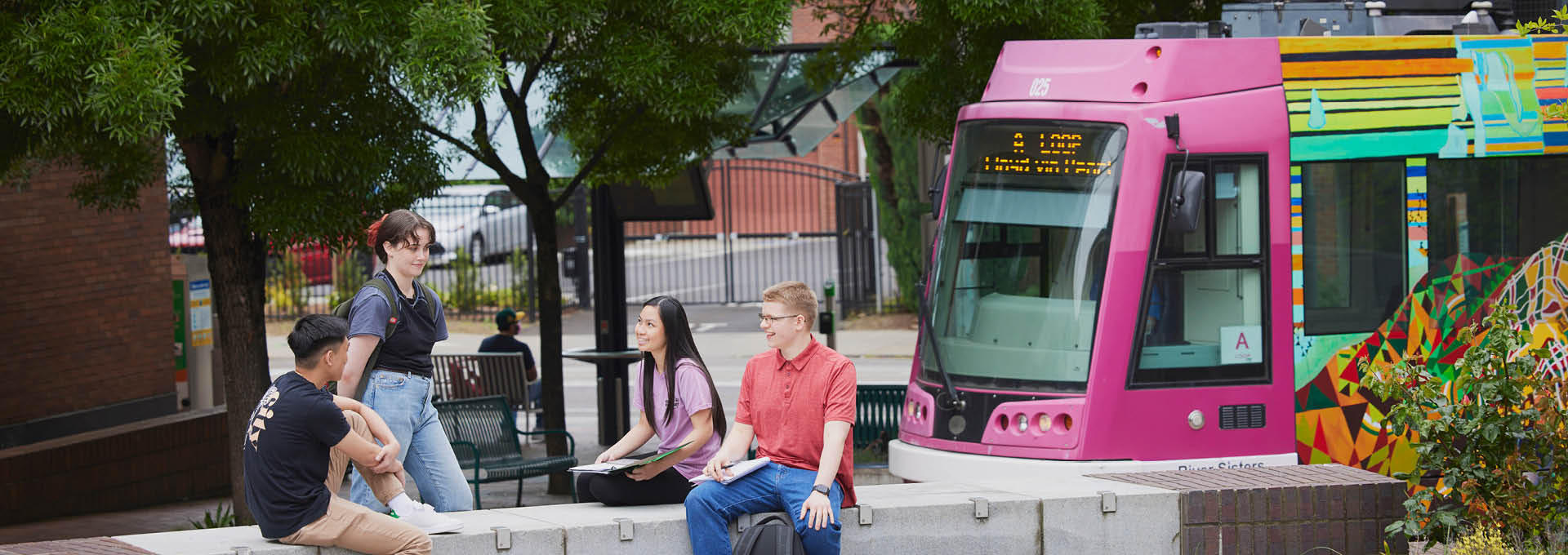 Students talking in Urban Plaza as the Streetcar goes by