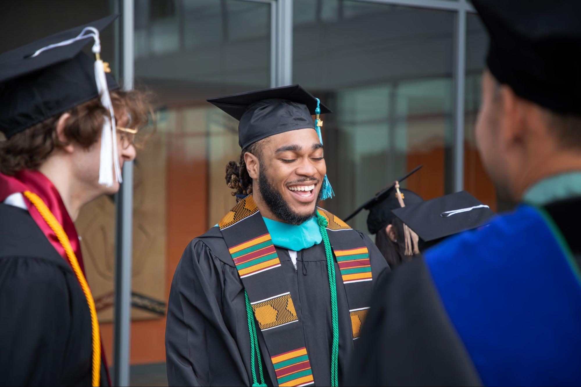 Three students in wearing commencement gowns and hets